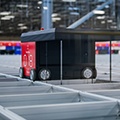 Hercules-AutoStore-redline-robot-closeup-retrieving-bin-on-AutoStore-grid-goods-to-person-automated-storage-system-thumb
