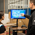 Bastian Solutions engineer showing Decathlon worker the touch screen HMI system